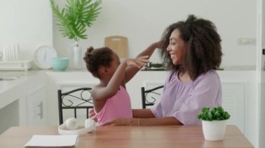 Cute little girl and her charming young mom hugging each other, smiling, enjoying family spend time together