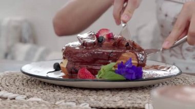 Tasty breakfast pancakes with blueberry and chocolate rotating on white wooden table
