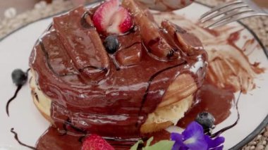 Tasty breakfast pancakes with blueberry and chocolate rotating on white wooden table