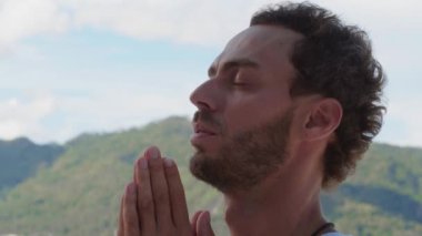 Headshot of a Caucasian man praying to god, meditating in the mountains, taking conscious breaths towards a better life