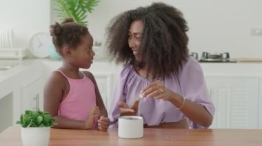 Loving mother teaching little daughter kid to save money, putting coin into pink piggy bank. Family finance, investment