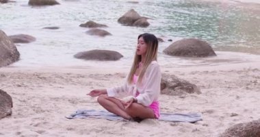 Asian teenage girl in casual wear are meditating sitting close the bith. Young woman doing yoga exercise for stress relief relaxing from work