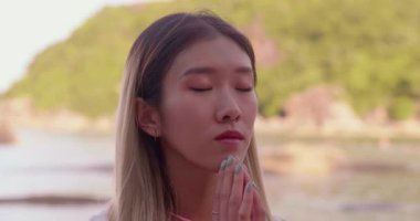 Gün batımında dua eden kadın. Asyalı kız elini güneşe uzatır ve dua eder.