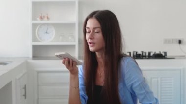 Kanepede oturan kadın evde akıllı telefonuyla kayıt yapıyor.