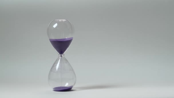 Скляний Пісочний Годинник Фіолетовим Піском Ізольованому Фоні — стокове відео