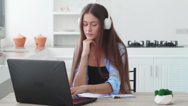 ヘッドフォンの女性はラップトップを見て オンラインで遠隔学習を持っています — ストック動画