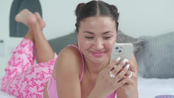 Красивая Очаровательная Молодая Азиатка Лежит Кровати Развлекаясь Своем Смартфоне Выходной — стоковое видео