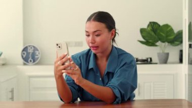 Asya kökenli güzel bir kadın akıllı telefon ve internet kullanıyor, arama yapıyor, evden bir video bağlantısı ile iletişim kuruyor.