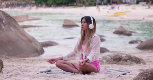 Mujer Asiática Joven Serena Auriculares Inalámbricos Sentado Pose Loto Playa — Vídeos de Stock