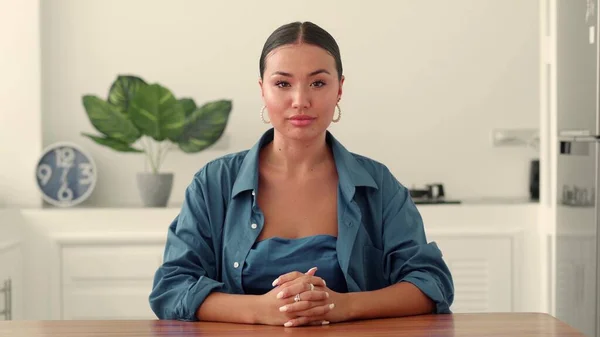 Çekici, çekici, çok ırklı, mavi elbiseli, kameraya özgüvenle bakan genç bir kadın. Ön görünüm