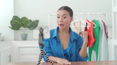 Cazibeli Asyalı kadın, moda tasarımcısı, moda tasarım atölyesindeki akıllı telefon vlog 'unda dikiş endüstrisi hakkında.