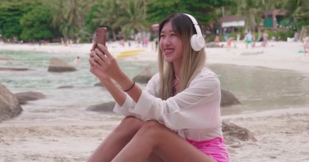Sjarmerende Asiatisk Kvinne Med Trådløse Hodetelefoner Avslappende Stranden Det Gøy – stockvideo