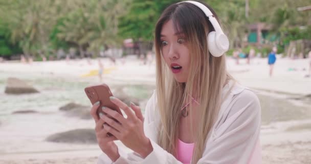 Fiatal Ázsiai Fülhallgató Hidegrázás Homokos Tengerparton Tapasztalatok Csodálkozás Szorítások Öklök — Stock videók