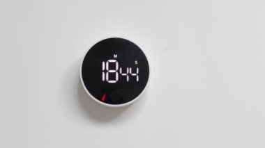 Duvara monte edilmiş, minimalist dizaynlı siyah beyaz saat, ters zaman tepkisi, beyaz bir duvara asılı.