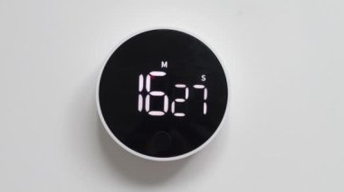 Siyah minimalist zamanlayıcı beyaz duvarda, zamanı tersine çeviriyor. Geri sayım başladı. Hızlı akan zaman kavramı.