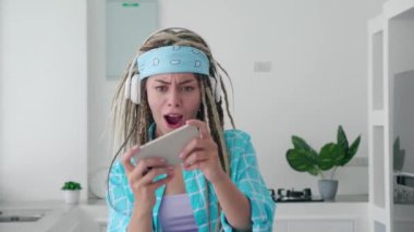 25 'li yaşlarda, kumar oynayan genç Rasta kadın cep telefonuyla poz veriyor. Modern arka plan stüdyosunun akıllı telefonlu bilgisayar oyunlarını kullanıyor. Halk yaşam tarzı konsepti.