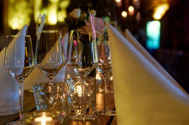 Şarap kadehleri ve ahşap bir masanın üzerinde beyaz bir peçete ile kurulmuş bir masa.