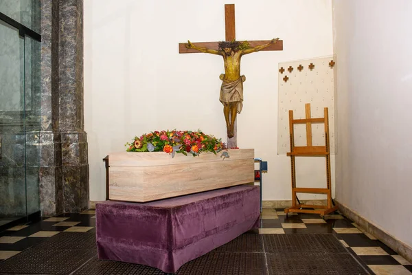coffin with flowers on it in church with Jezus Christ against the wall waiting to be transported for the service