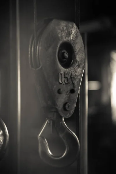 Metal hook from a crane against the background of a workshop. A piece of metal curved or bent back at an angle, for catching hold of or hanging things on.