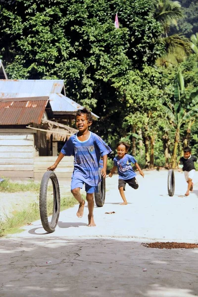 Maluku, Endonezya-25 Mayıs 2015. Çocuklar güpegündüz Endonezya, Maluku 'da kullanılmış lastiklerle mutlu bir şekilde oynuyorlar..