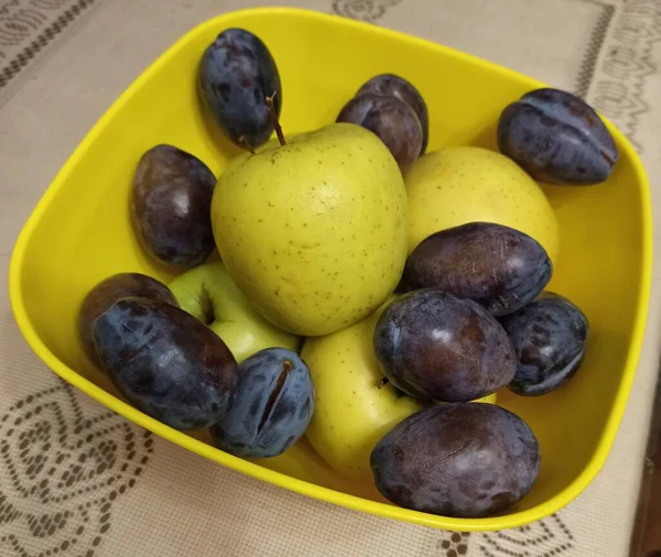 Tahta arka planda bir kasede taze erikler.