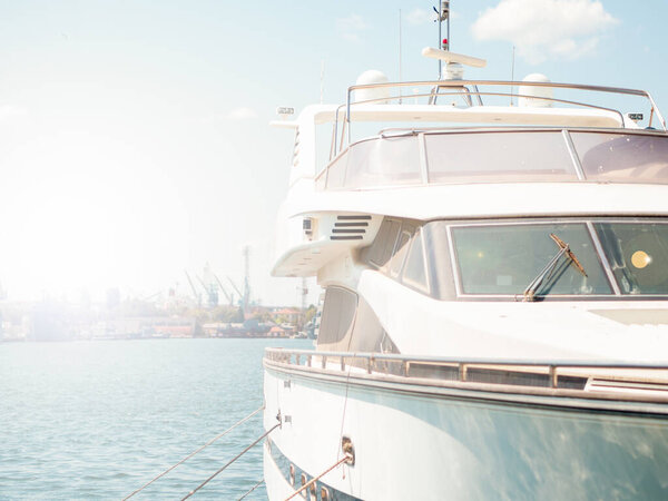 Ancored luxury motor yacht on a pierce, front view. Maintenance and repair of expensive yachts, yacht rental and boat trips.