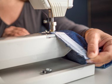 Evde kilitli küçük bir işletme var. Dikiş makinesiyle çalışan terziye yaklaş.