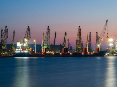 Geceleyin sanayi konteynırı deniz limanı. Kuru deniz tankeri yüklemesi.