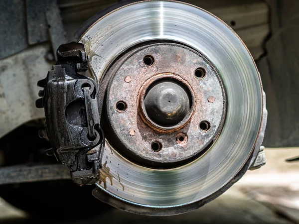 Closeup weared overheated brake disk and detail of wheel hub. Replacing brake pads in car service.
