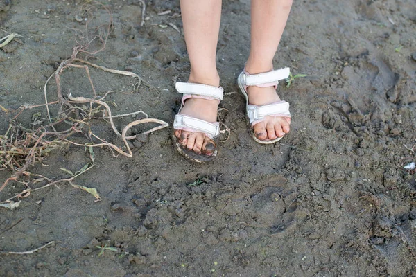 Beyaz sandaletlerle çamurda çocukların ayakları