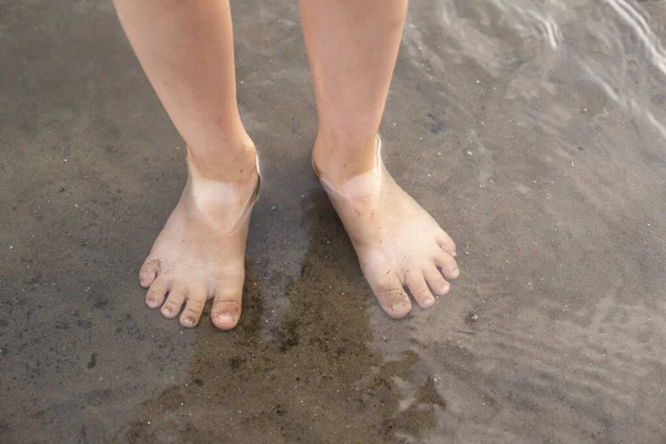 Çocukların ayakları nehrin suyunda duruyor.