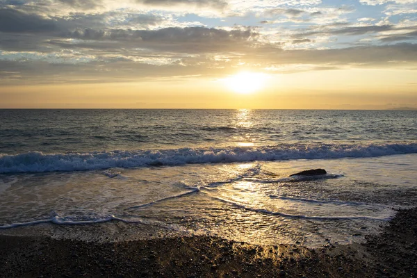 Güzel, turuncu gün batımı güzel bulutlar ve kayalar kıyıda.