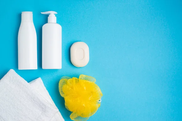 Beyaz havlular, beyaz şampuanlar, sabun, mavi üzerine sarı bez.