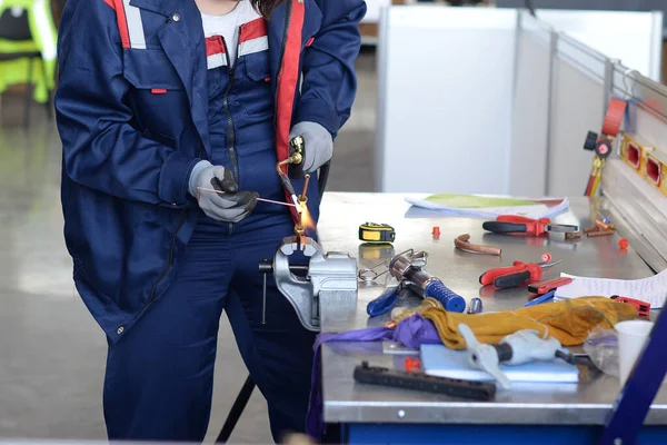 Mavi takım elbiseli bir işçi içeride kaynak yapıyor.