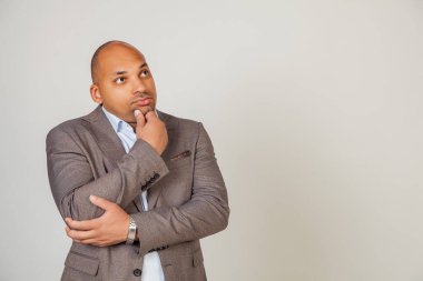 Ciddi düşünceli Afrikalı erkek, çenesine dokunuyor, yana bakıyor, yaratıcı fikirler arayışında bir çözüm düşünüyor. İş sorunlarını çözer ya da çözüm kavramı benimser