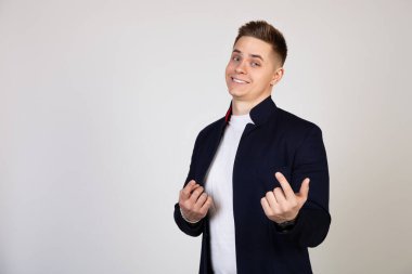 Genç bir adam, yakışıklı bir adam onu parmağıyla çağırıyor. Parmağını kıpırdatarak yaklaşır, yanına yaklaşır, beyaz arka planda durup kameraya bakar.