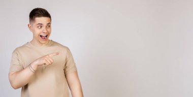 Adam yan tarafı gösteriyor ve gülümsüyor. Genç, çekici, yakışıklı, modern serbest çalışan, girişimci, kameraya bakan işveren öğrencinin fotoğrafı, işaret parmağıyla mekanı kopyalamak için işaret ediyor