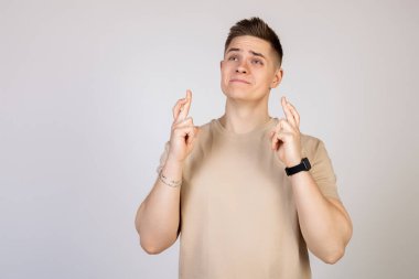 Genç, gergin, heyecanlı bir adamın fotoğrafı. Parmaklarını çapraz yapmış. Elleri tedirgin bir yüz ifadesiyle bağlı olan adam.