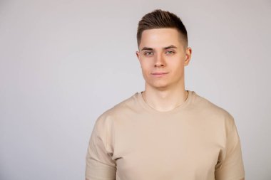 Yakışıklı, şık saç stili olan genç adam kameraya ciddi bir ifadeyle bakıyor. Çekici, yakışıklı, modern serbest çalışan, girişimci ve kameraya bakan işveren öğrencinin fotoğrafı.