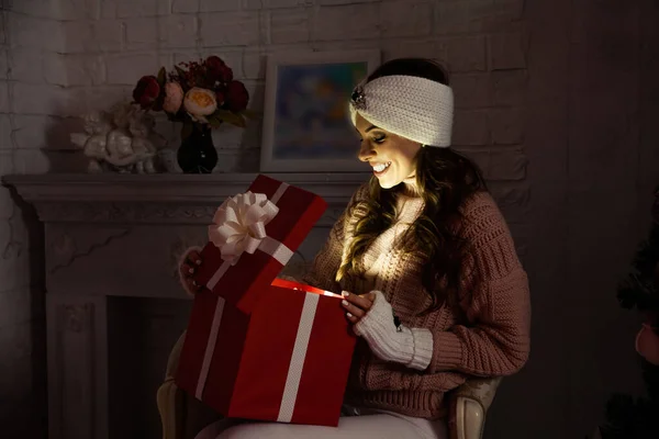 선물을 가지고 크리스마스 선물 상자를 여는 행복 한 젊은 여성. 빨간 배경에 고립된 선물 상자를 여는 행복 한 미소짓는 소녀의 모습. — 스톡 사진
