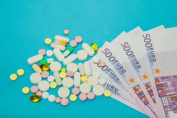 Medicine pills over euro banknotes on a blue background. Covid-19 coronavirus pills are on the euro banknote. The concept of insurance medicine, insurance, high cost, high cost of drugs. — стоковое фото