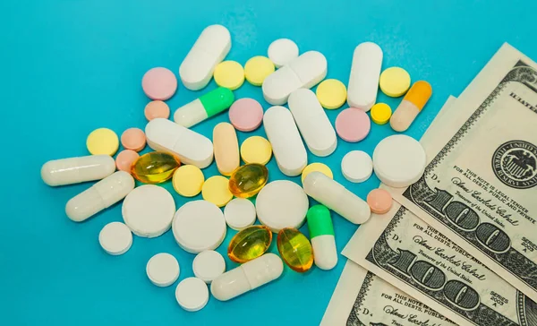 Des cachets. Pilules de médicaments sur des billets d'un dollar sur un fond bleu Les pilules de coronavirus Covid-19 sont en billets de cent dollars. Le concept de médecine d'assurance, assurance, coût élevé élevé des médicaments. — Photo