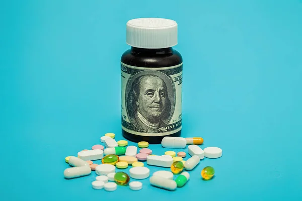 Pengar och piller av olika färger på en blå bakgrund. Ökningen av kostnaderna för sjukvård. Begreppet försäkringsmedicin, försäkring, höga kostnader, höga kostnader för läkemedel. — Stockfoto