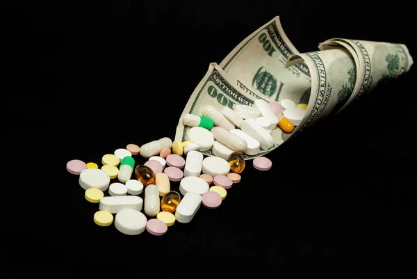 Dinero y pastillas de diferentes colores sobre un fondo negro. El aumento en el costo de la atención médica. El concepto de medicina de seguros, seguros, alto costo, alto costo de medicamentos. — Foto de Stock