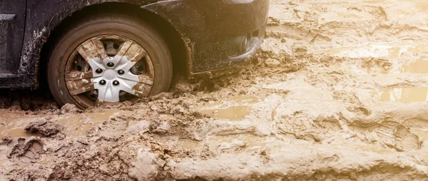 Das Auto blieb auf einem Feldweg im Schlamm stecken. Das Rad eines Autos blieb im Schlamm auf der Straße stecken. Auto auf einem Feldweg. — Stockfoto