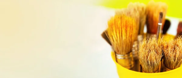 Um conjunto de pincéis para pintura com tintas. Muitas escovas em um suporte de metal amarelo — Fotografia de Stock