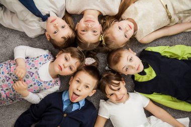 Erkekler ve kızlar daire oluşturun. Mutlu çocuklar eğleniyor. Çocuklar birlikte yatıyorlar. Mutlu çocuklar elleri ile bir daire içinde yerde yatıyorlar. Üst Manzara. Bir grup çocuk yerde uzanmış gülümsüyor.