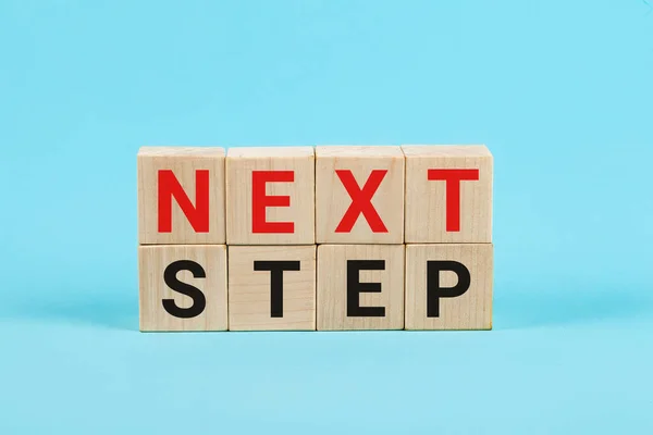 Next Step koncept med alfabetet bokstäver på trä kuber Utbildning och företag start koncept. Orden Nästa Steg på små trätärningar, Blå bakgrund — Stockfoto