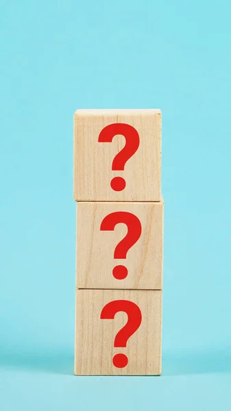 PERGUNTA A forma de um bloco de cubo de madeira com um símbolo de ponto de interrogação em um fundo azul. Os pontos de interrogação no bloco de madeira Fotografias De Stock Royalty-Free