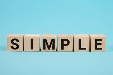 Kolaylaştırmak için basit bir kelime, ahşap bloklardan harflerle, basit bir kavram, mavi arkaplan.